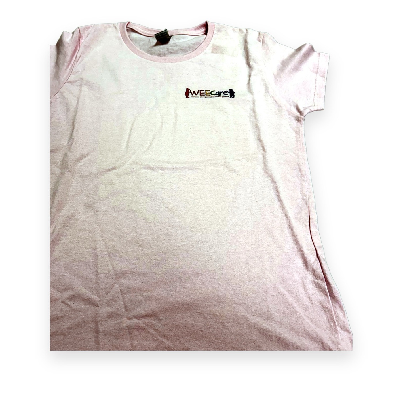 Light pink tee with a small WEE Care ministry logo on the chest