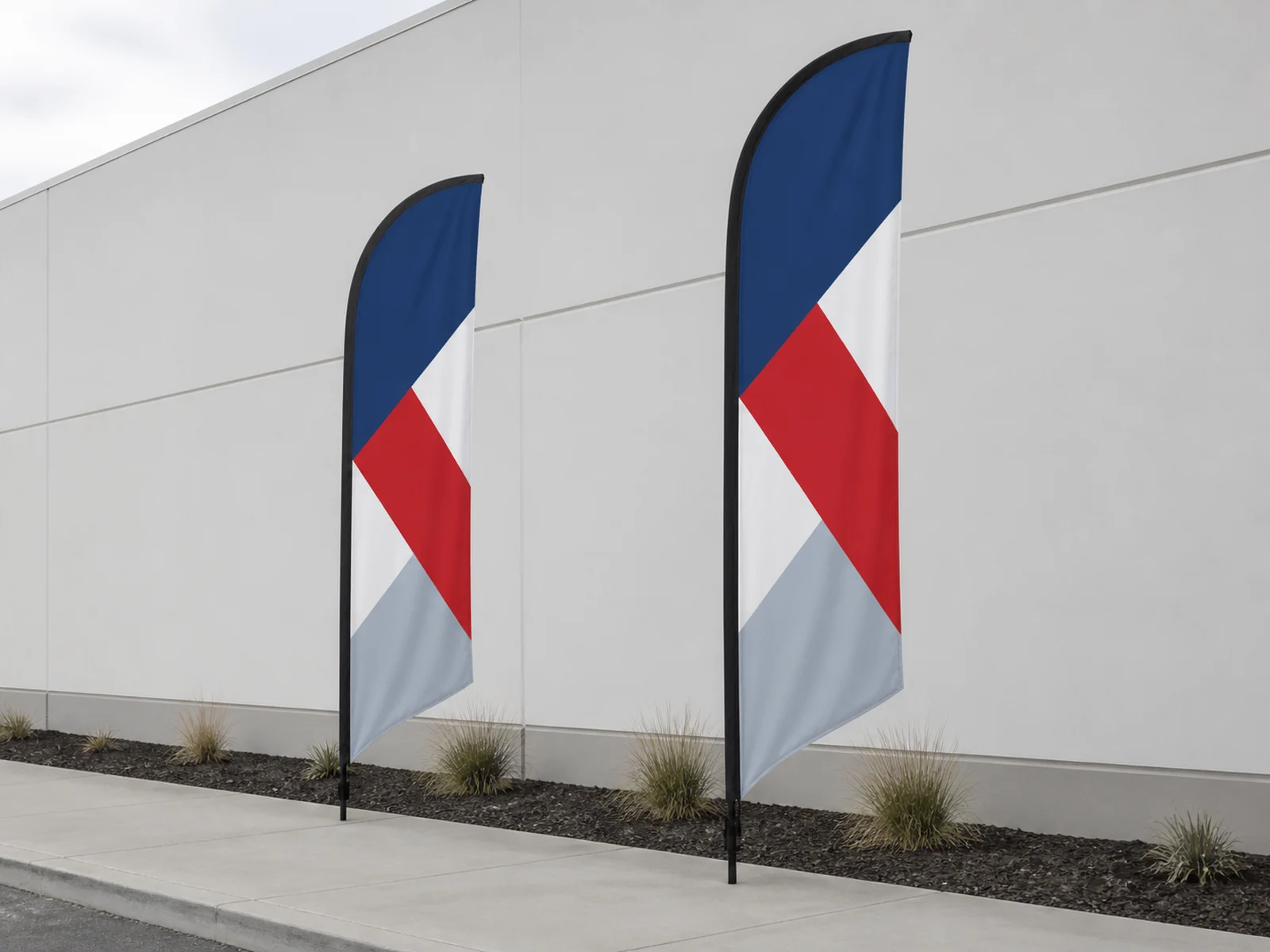 Two feather flags planted along a walkway in front of a plain storefront