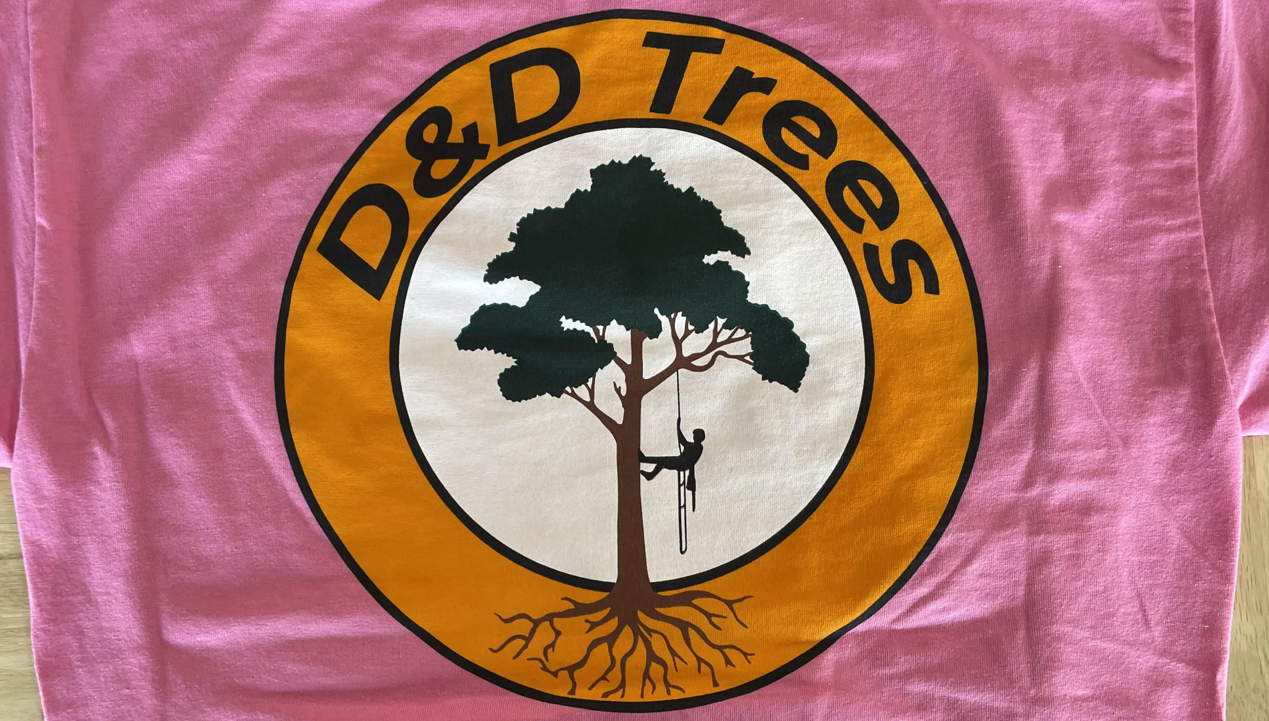 A pink shirt with a multi colored screen printed logo.
